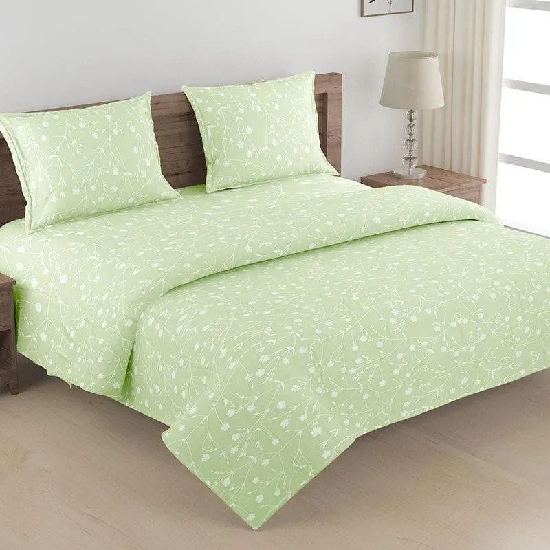 Green floral bedding set spread across a bed in a bright bedroom