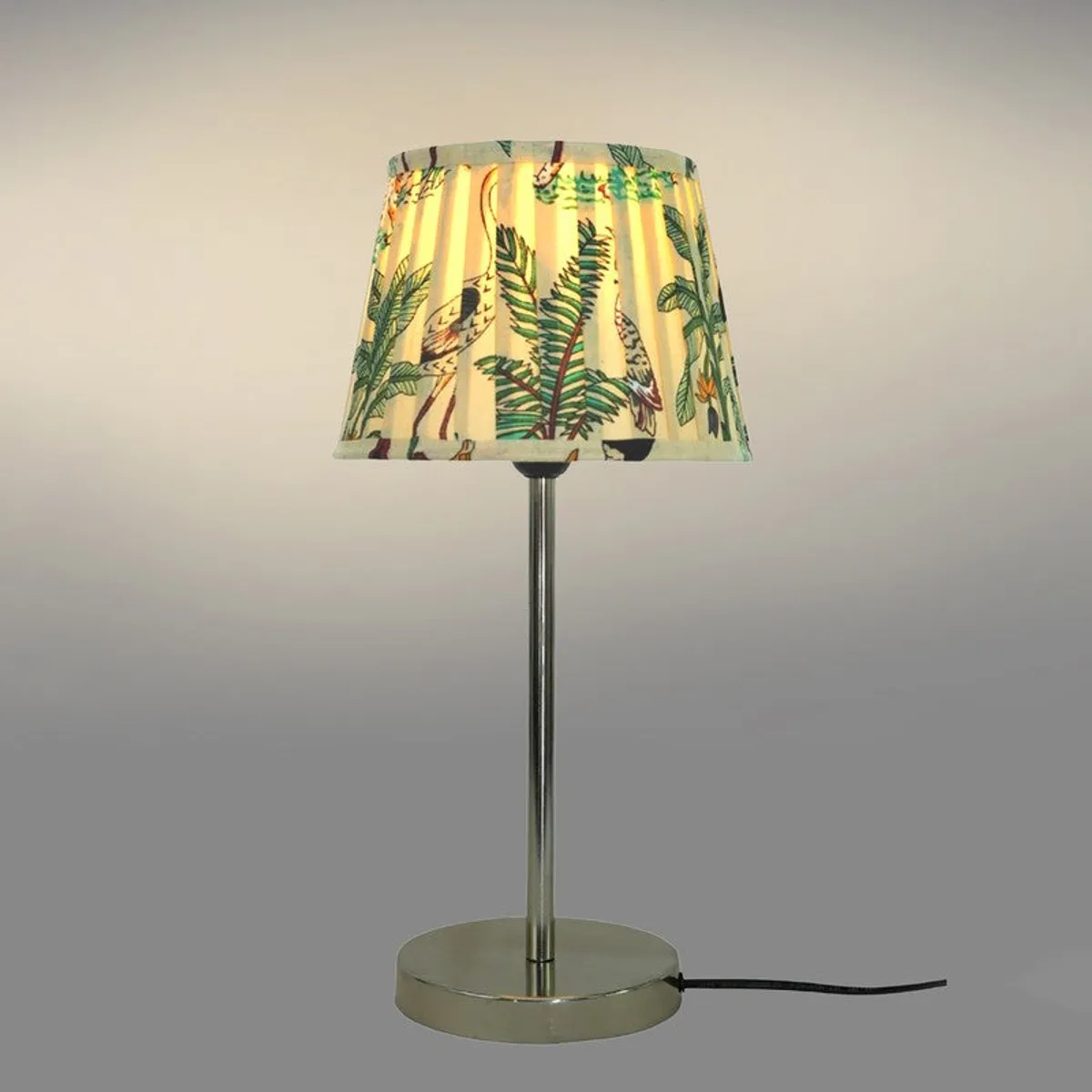Full table lamp showing tropical shade, slim metal stem and round base