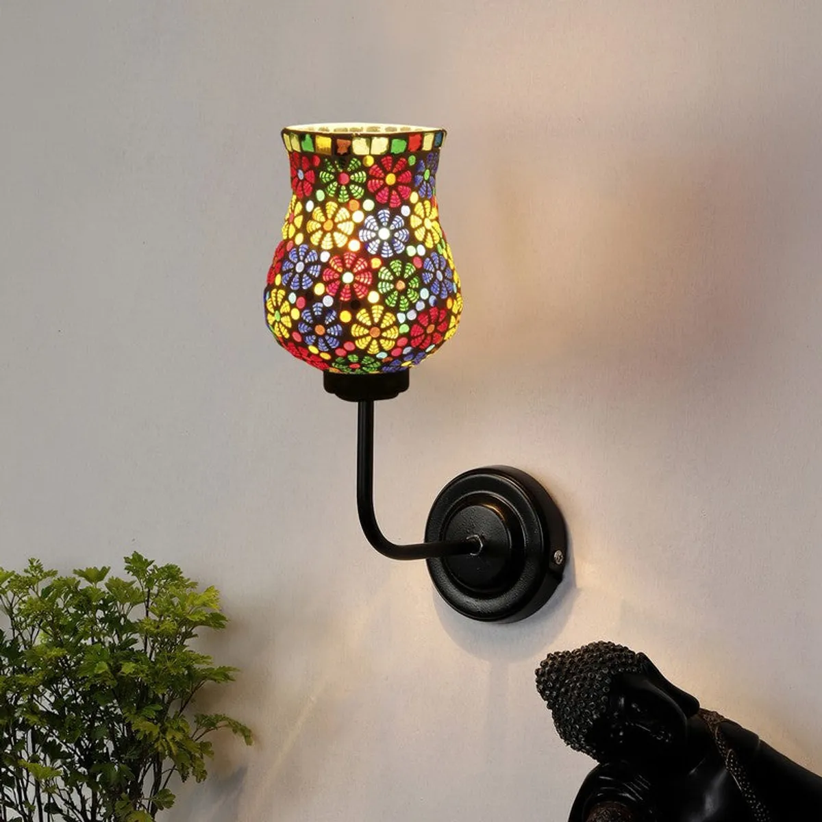 Lit multicolour mosaic wall lamp with black iron arm on white wall