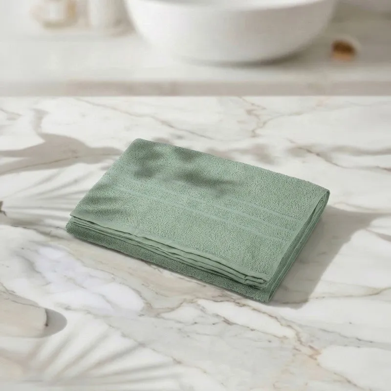 Folded sage green bath towel on a marble surface