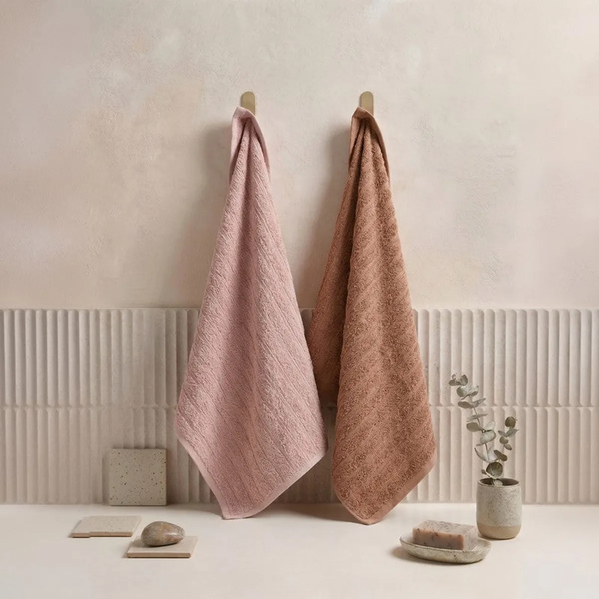 Peach and brown towels hanging in a neutral bathroom setting