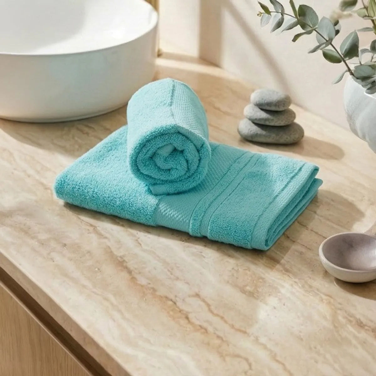 Folded turquoise plush towel set displayed on a marble bathroom counter