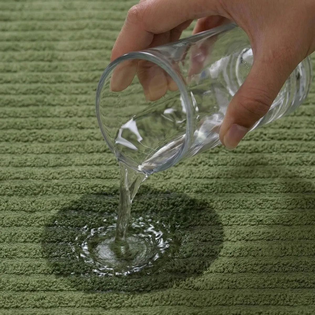 Water poured onto a green textured towel surface