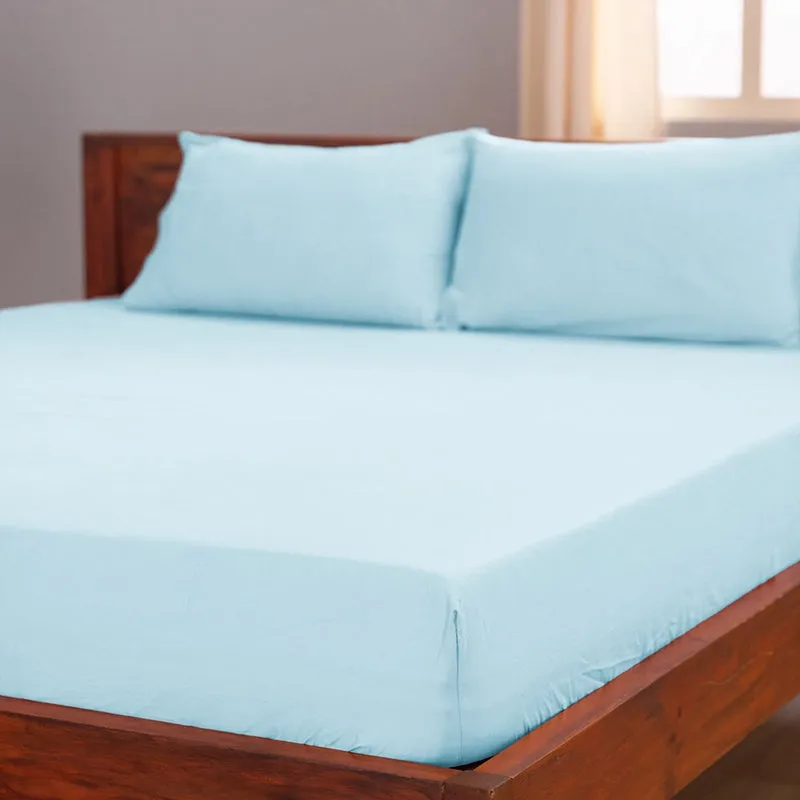Pale blue pillow covers styled on a wooden bed in a bright room.