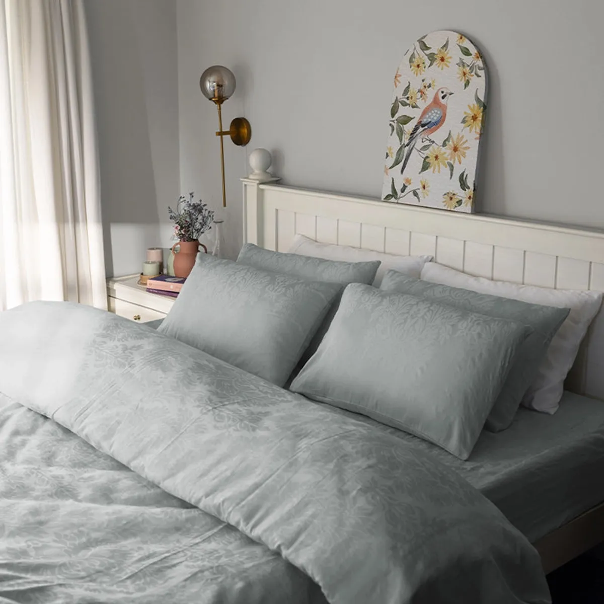 Light grey floral bedding styled in a bright bedroom