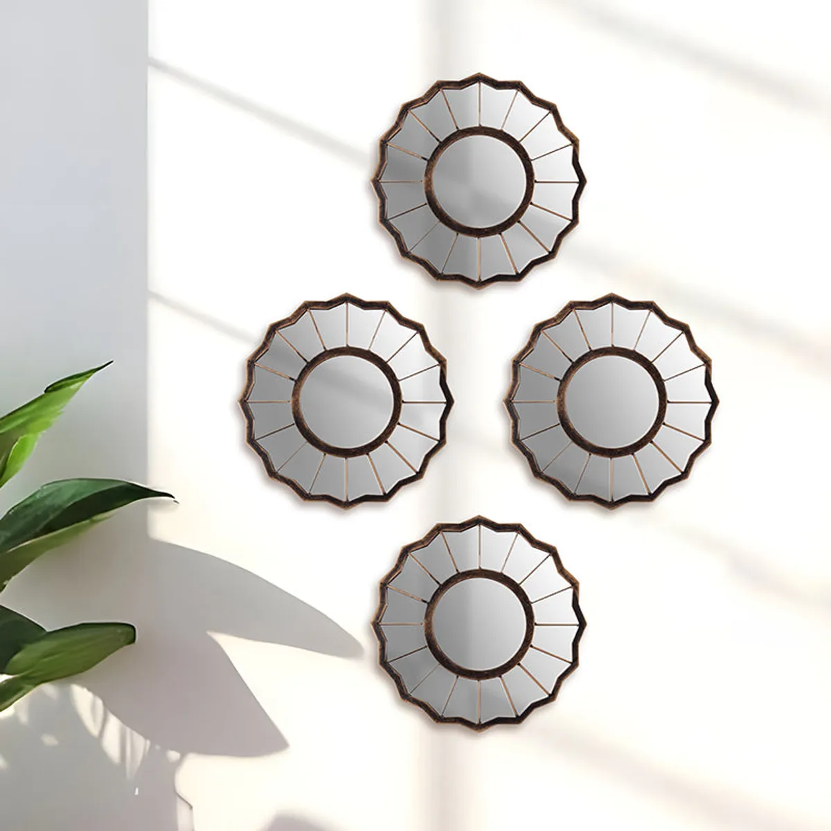 Set of four round sunburst wall mirrors with copper-toned frames on a white wall