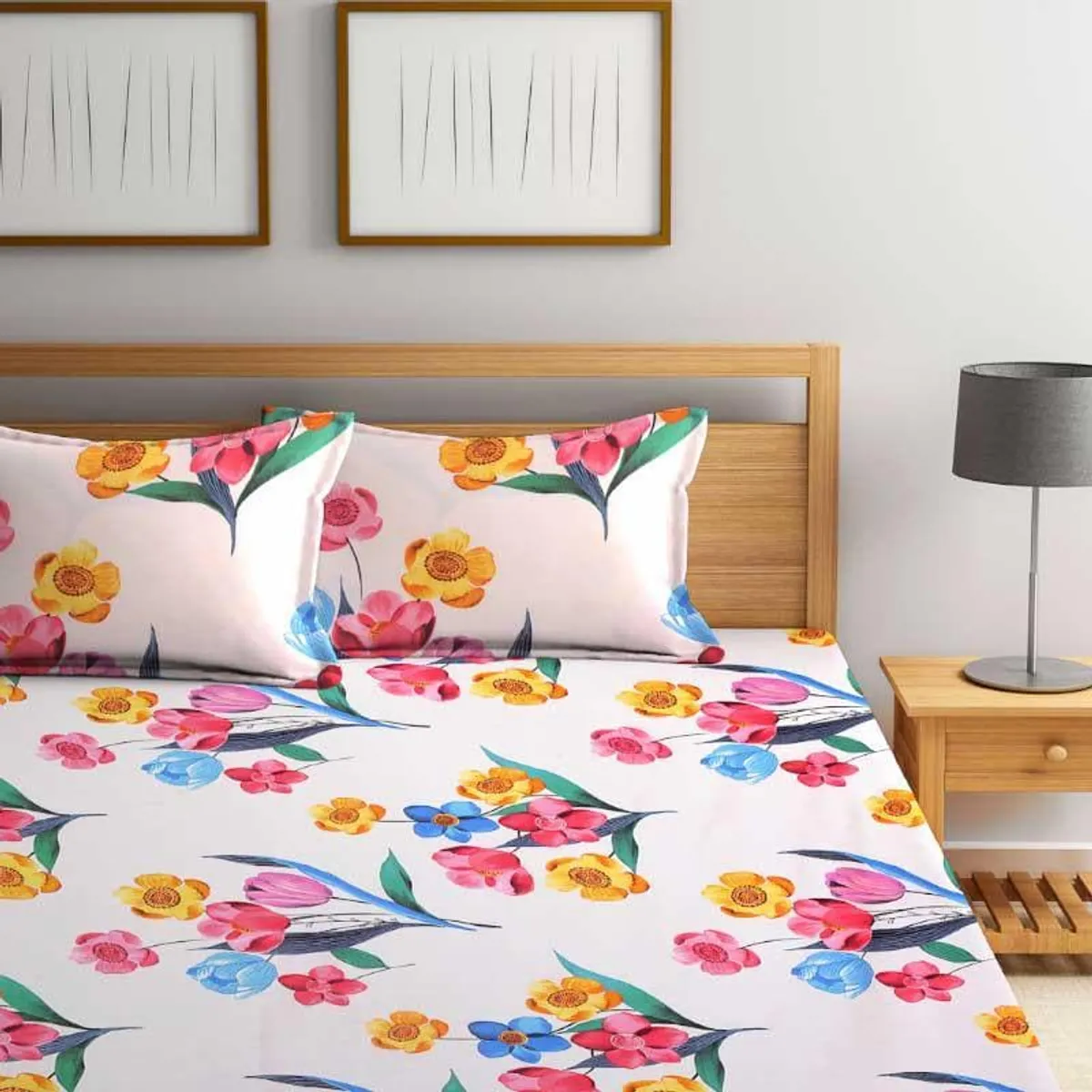 White bedsheet and pillow covers with colourful floral prints on a wooden bed