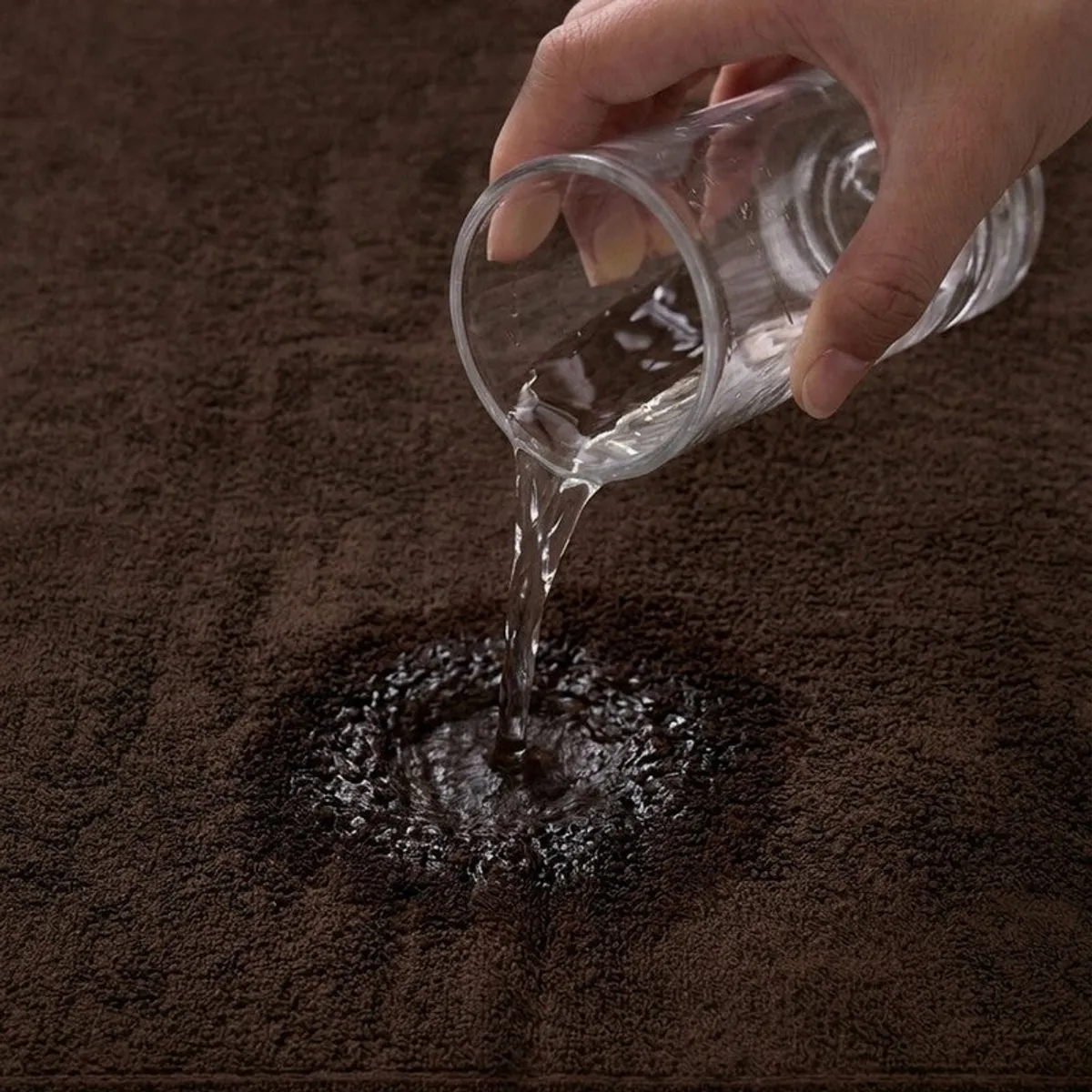 Water being poured onto the absorbent surface of a brown towel