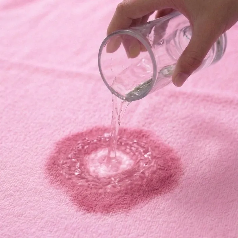 Close-up of water poured onto a light pink towel