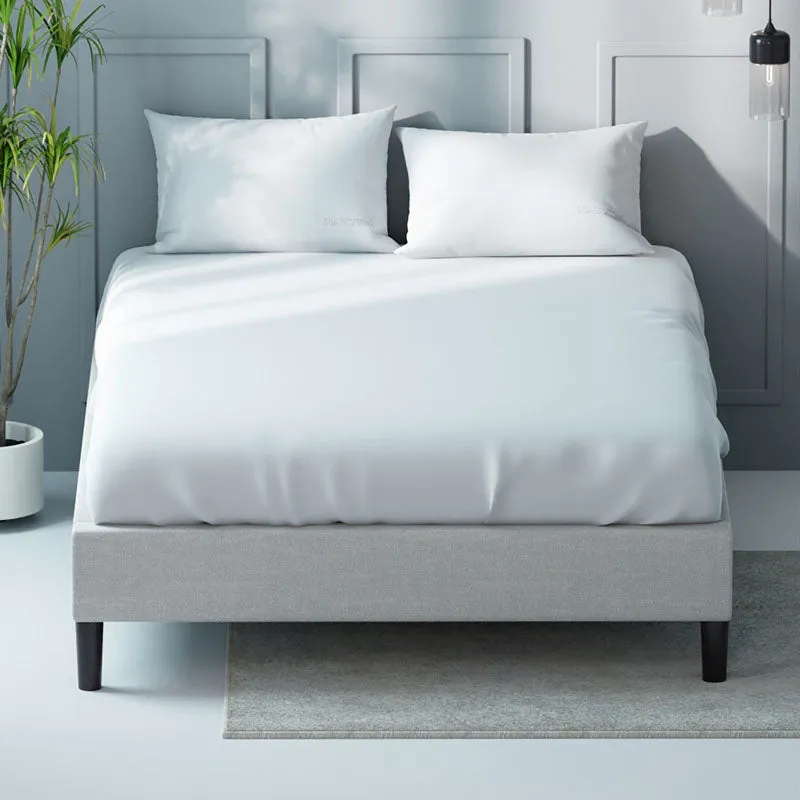 White bedsheet and pillows arranged on a grey upholstered bed