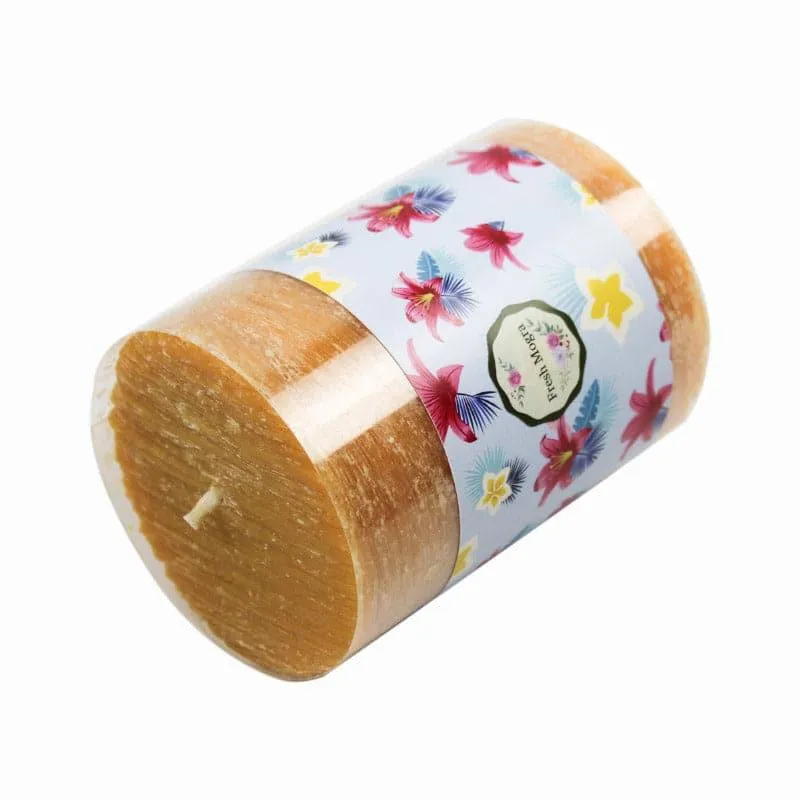 Brown pillar candle placed sideways showing floral wrap detail
