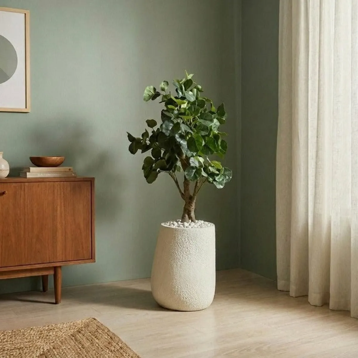 Tall leafy plant arranged in the white floor planter beside a cabinet