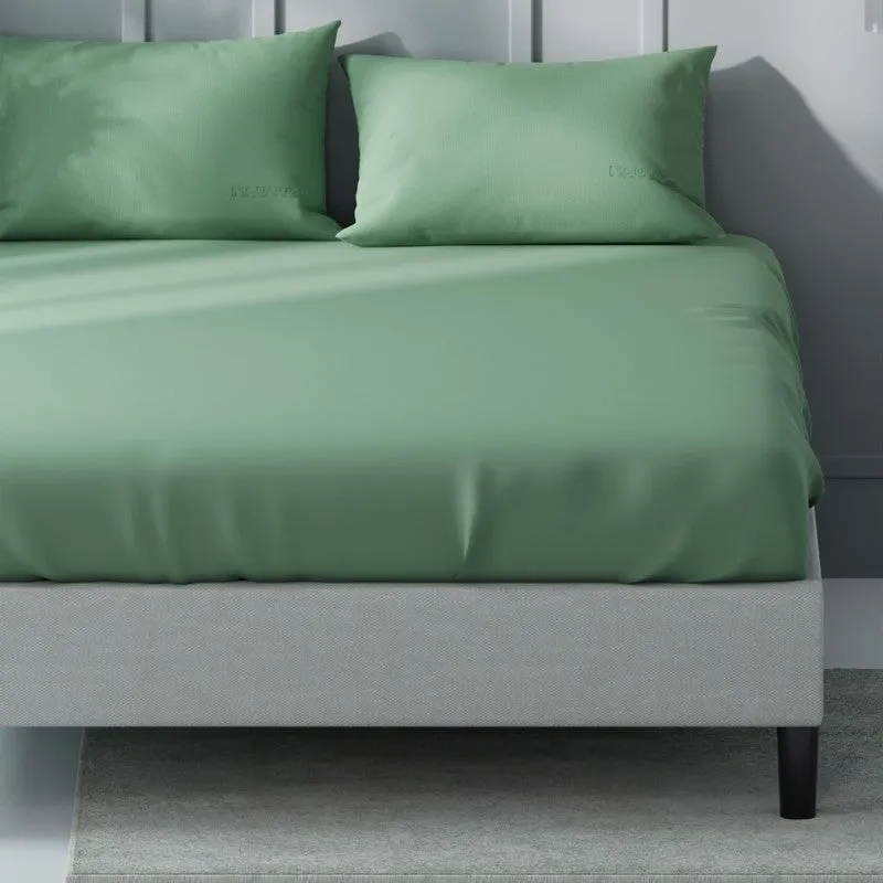 Close view of a smooth green bedsheet draped over a bed