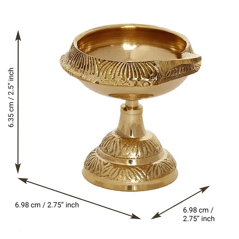 Gold brass diya with a lit wick shown in close-up against a warm background.