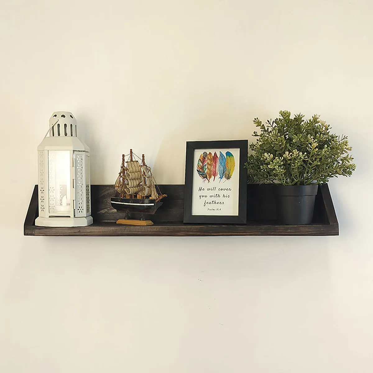 Brown wooden wall shelf displaying a lantern, model ship, framed art and potted plant.