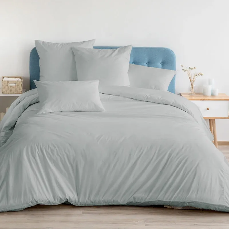 Light grey bedding set with matching pillow covers on a blue headboard bed