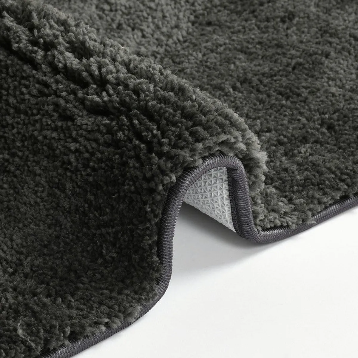 Folded corner of the black bath mat showing thick pile and backing