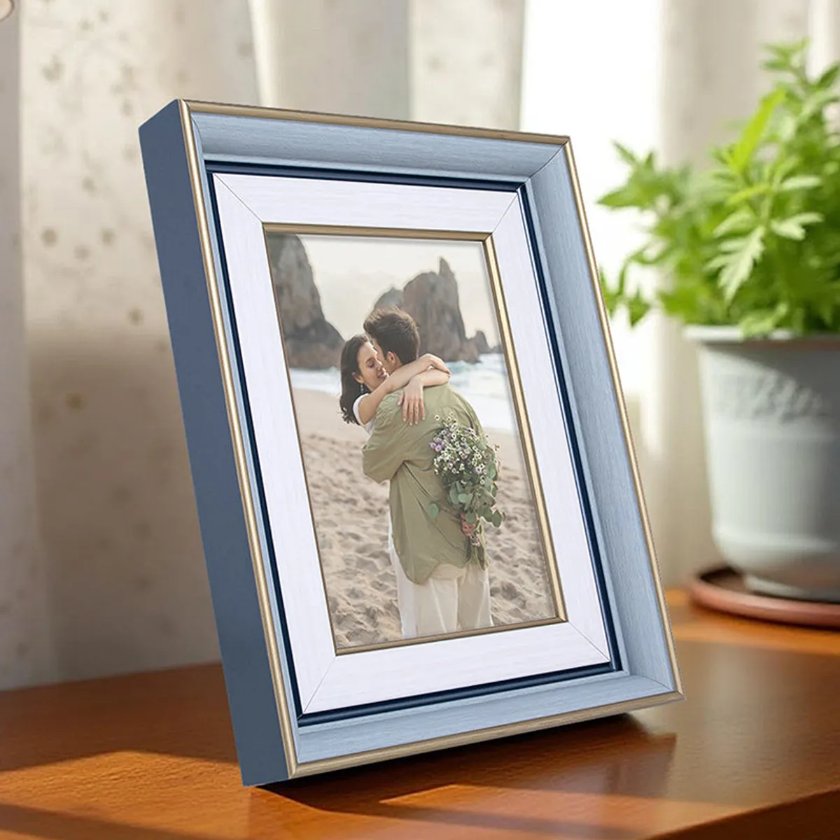 Blue and white rectangular photo frame displayed beside a potted plant