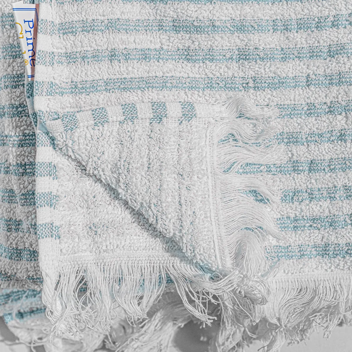 Close-up of blue and white striped towel fabric with fringed edges.