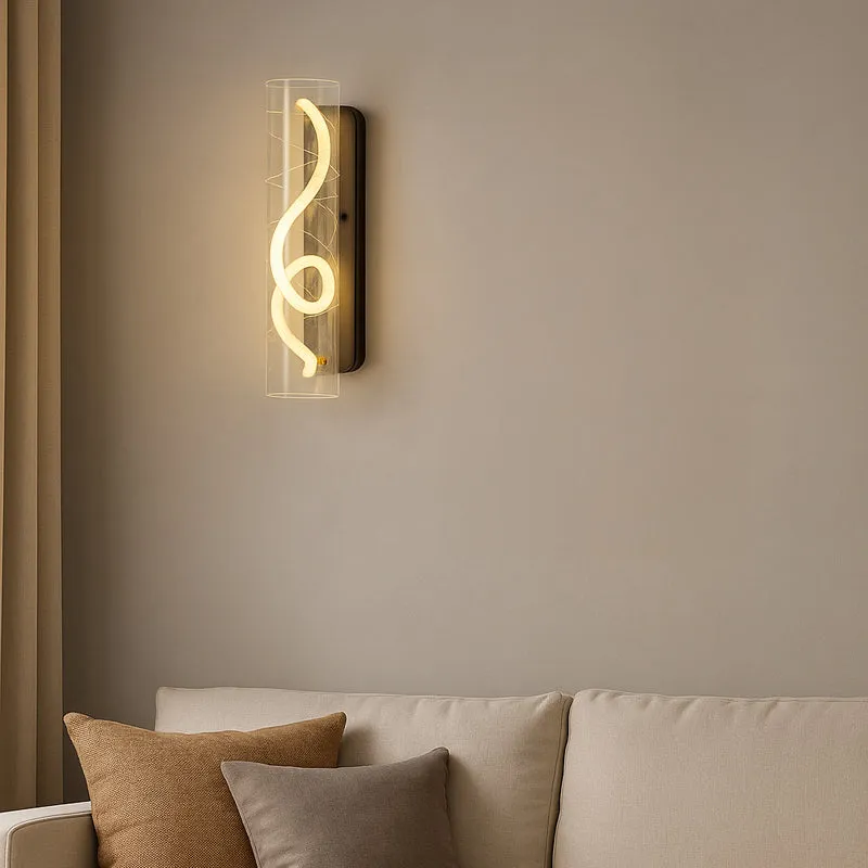 Transparent cylindrical wall lamp mounted above a cream sofa with neutral cushions