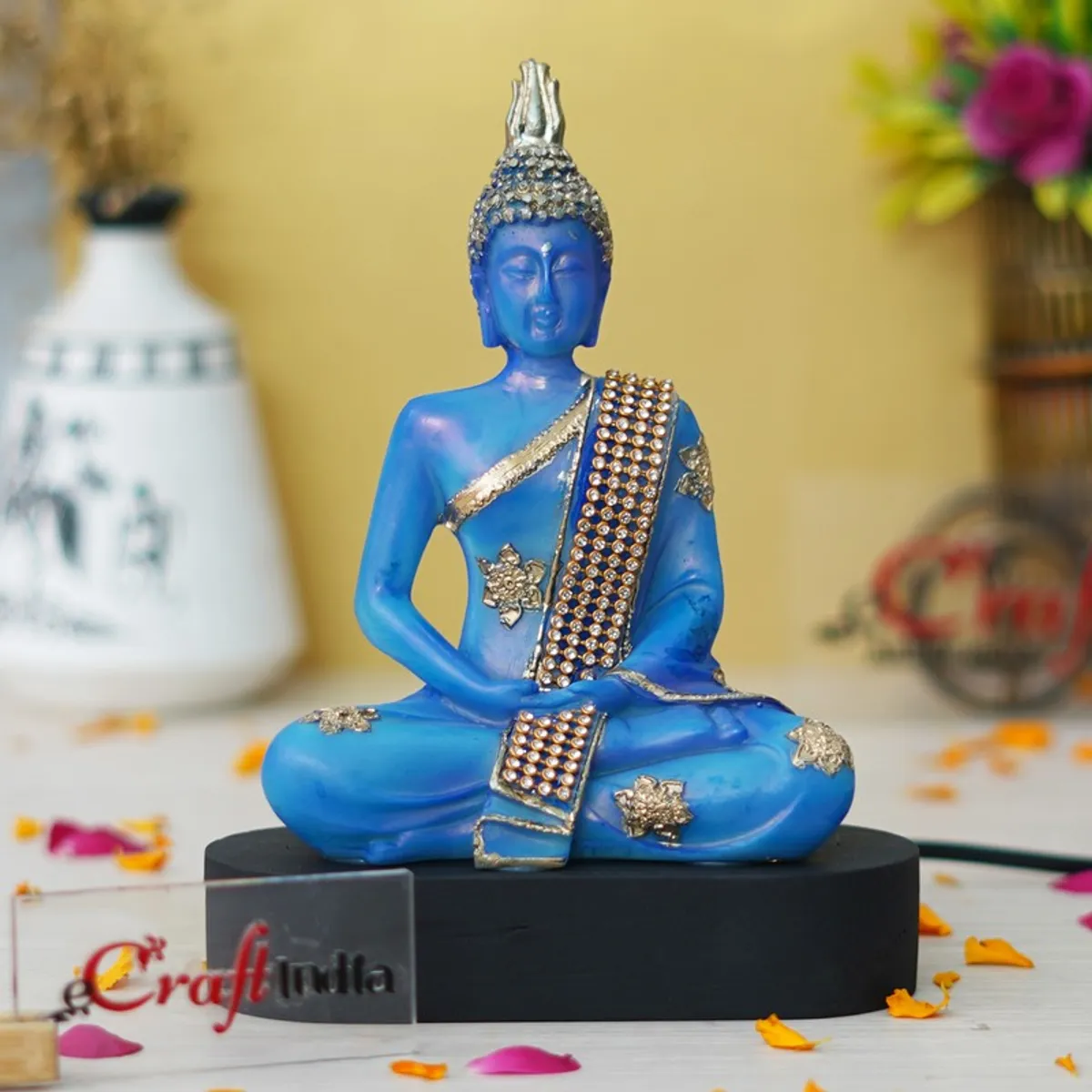 Blue Buddha idol with gold accents displayed on a black base