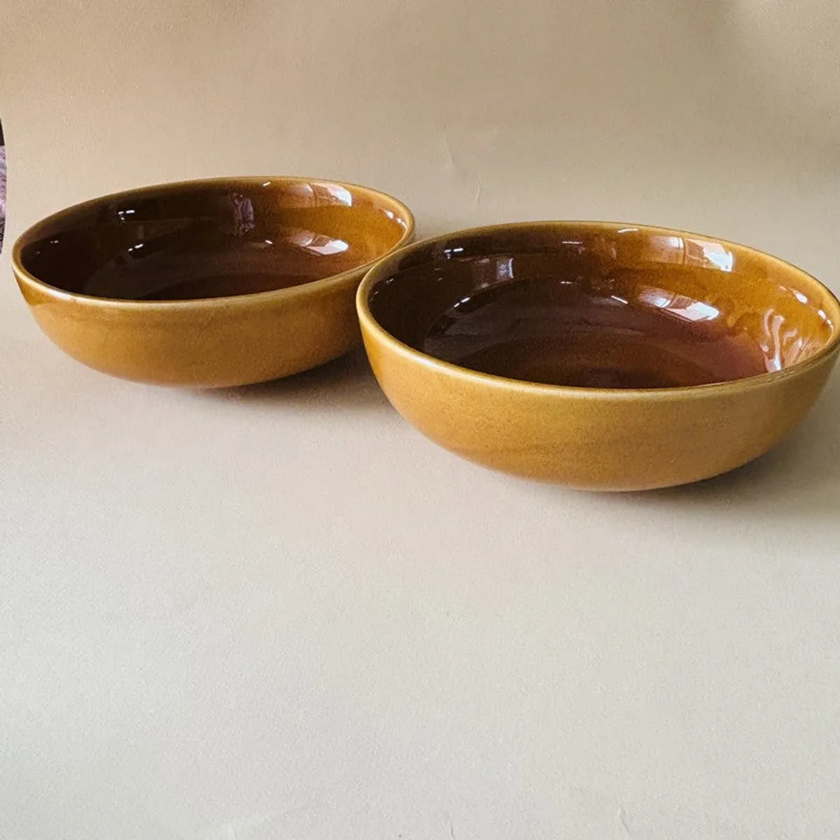 Two brown ceramic serving bowls placed side by side