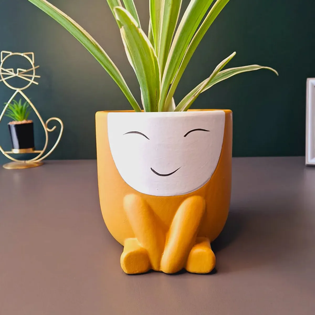 Front view of orange character planter with green leaves
