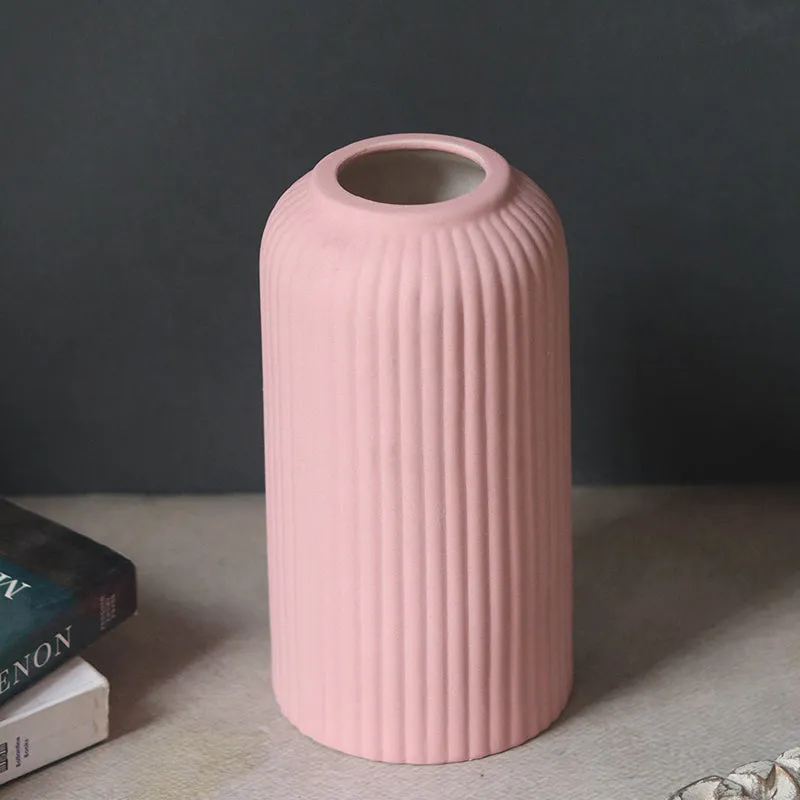 Close view of a pink ribbed ceramic vase on a tabletop beside books