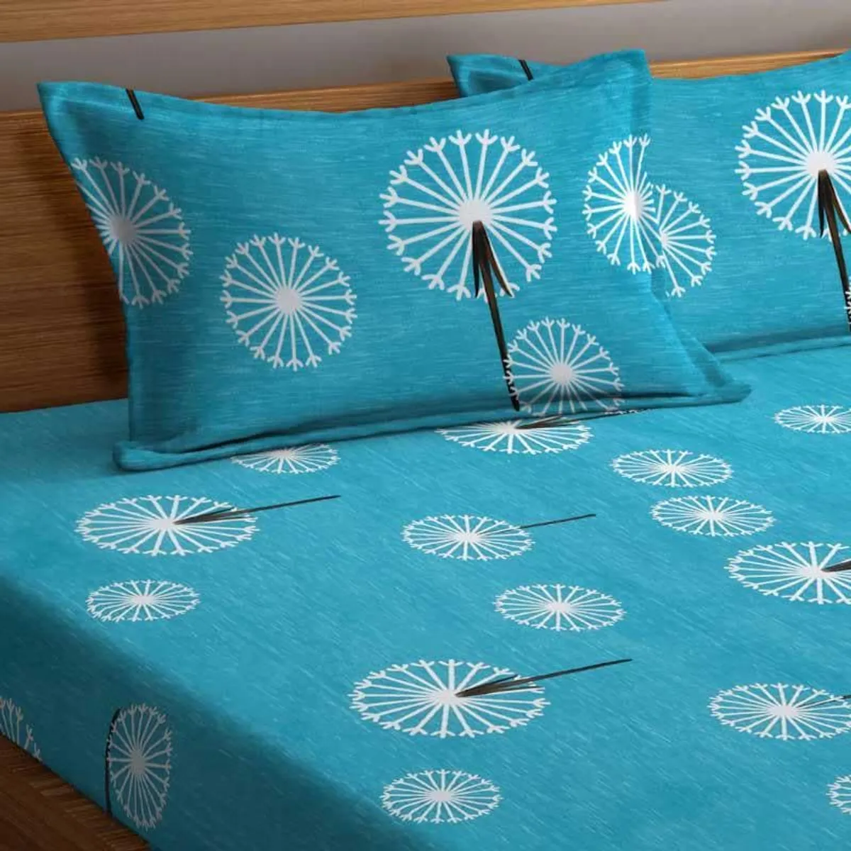 Blue bedsheet and pillow covers with white dandelion motifs on a bed