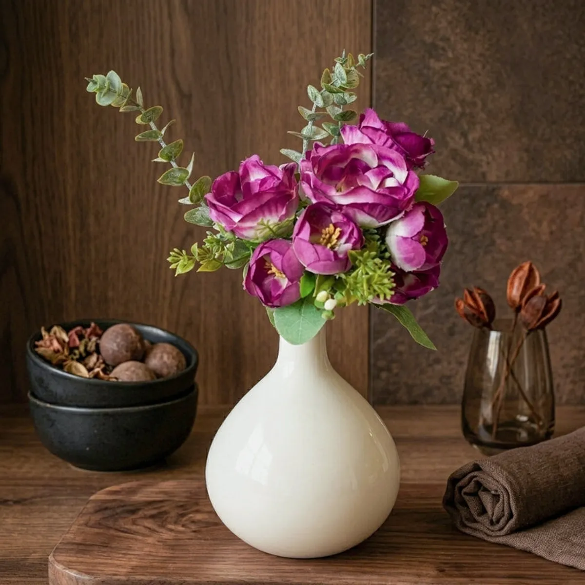 White vase with purple flowers styled on a dark wooden tabletop
