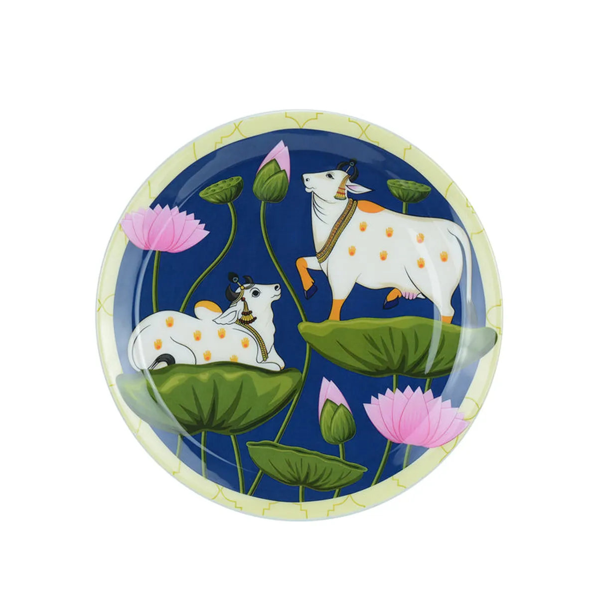 Round wall plate showing two decorated cows among lotus flowers on a blue background