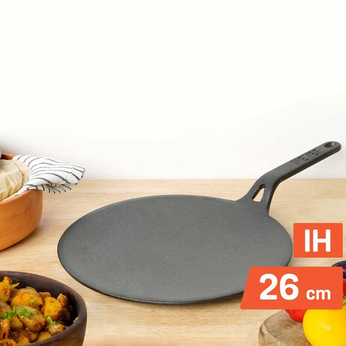 Black cast iron tawa displayed on a kitchen counter with food nearby