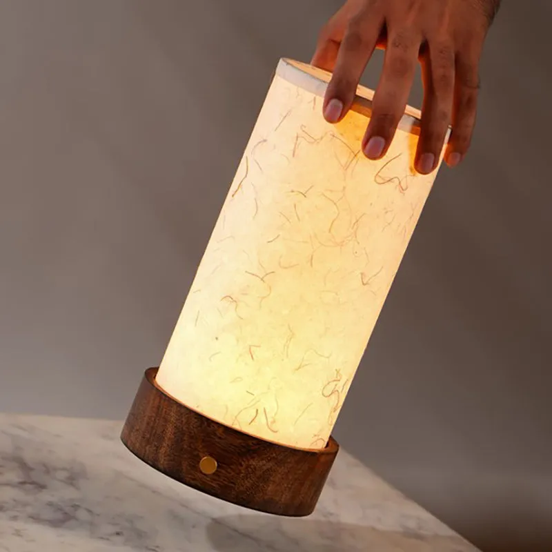 Hand lifting the glowing ivory lamp with wooden base