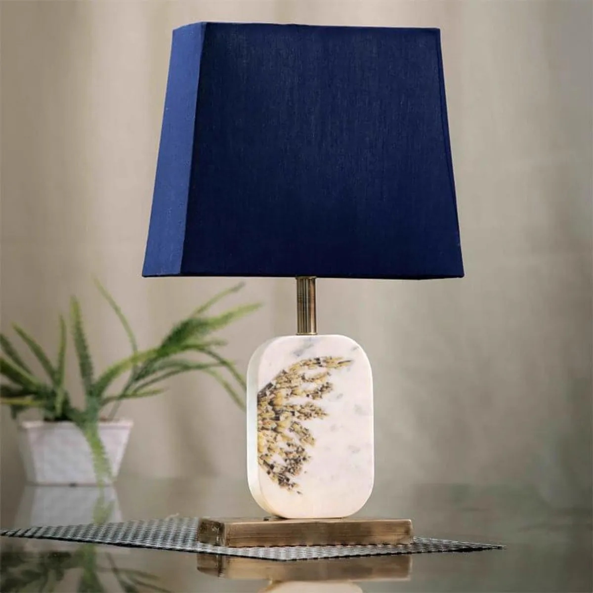 Blue fabric table lamp with veined marble base on a wooden platform