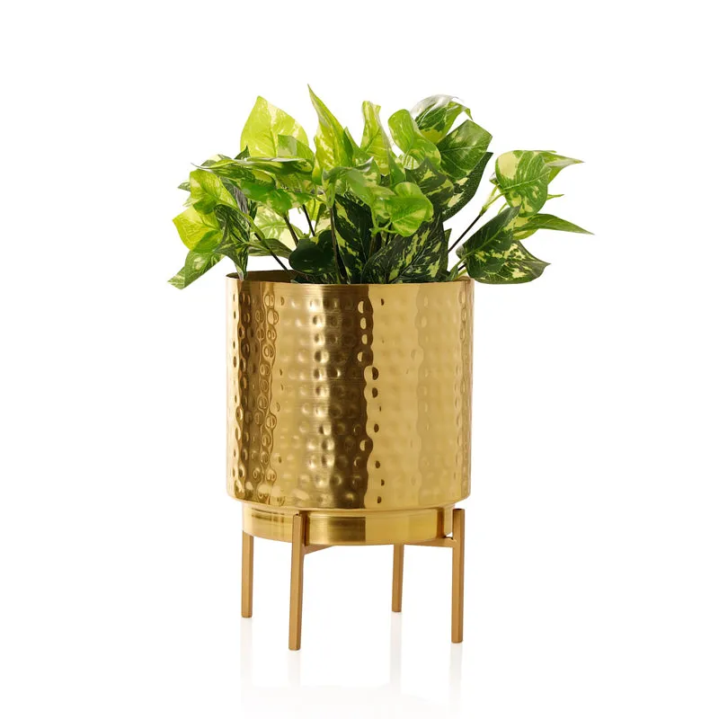 Gold hammered planter on stand with leafy plant