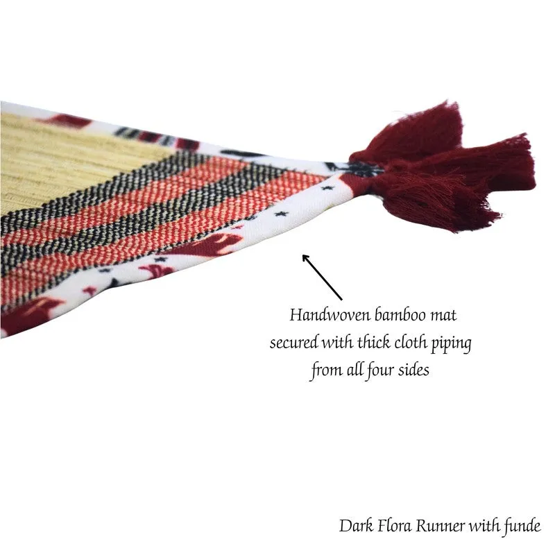 Close-up of bamboo table runner edge with red tassels and patterned fabric piping
