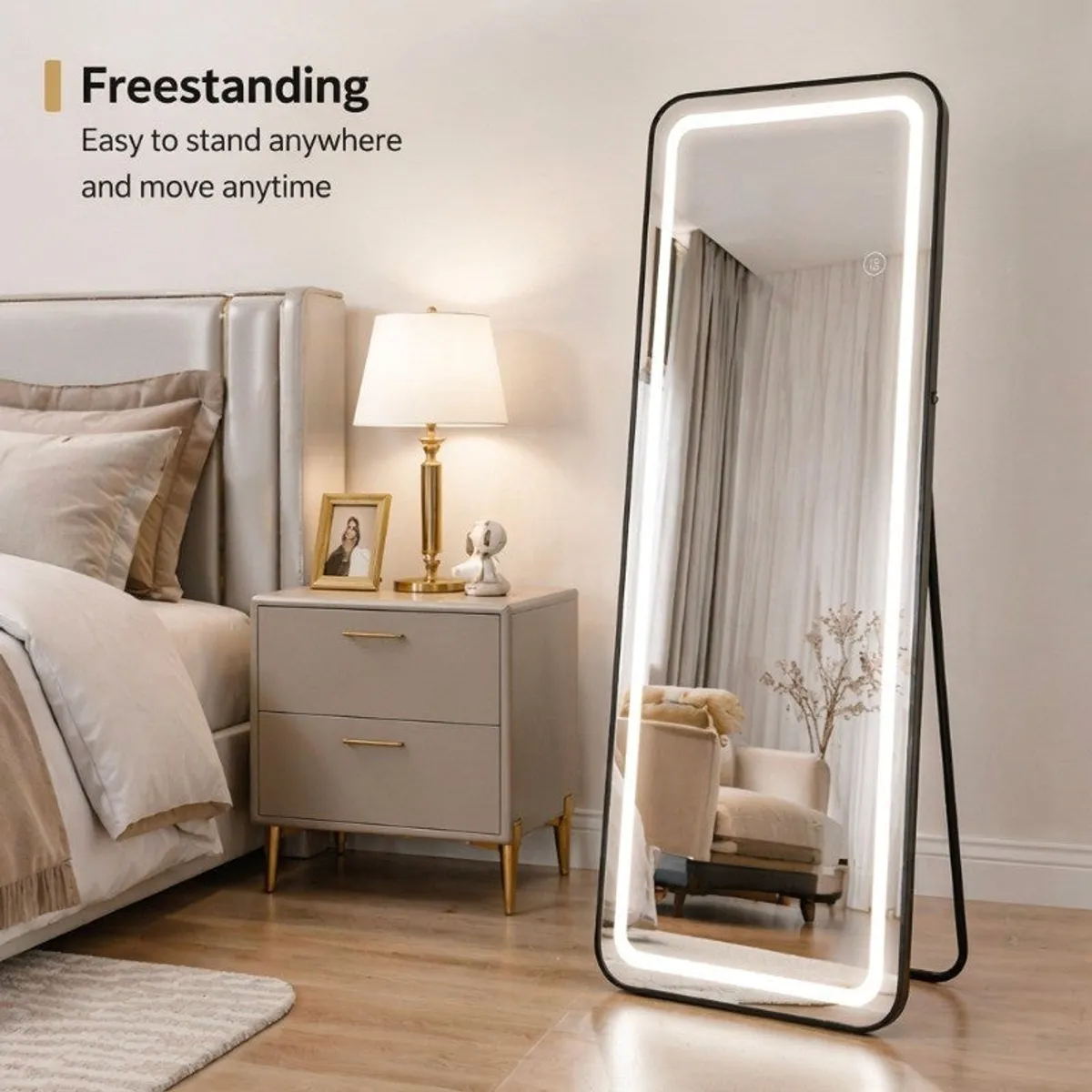 Illuminated floor mirror standing beside a bed in a neutral bedroom.