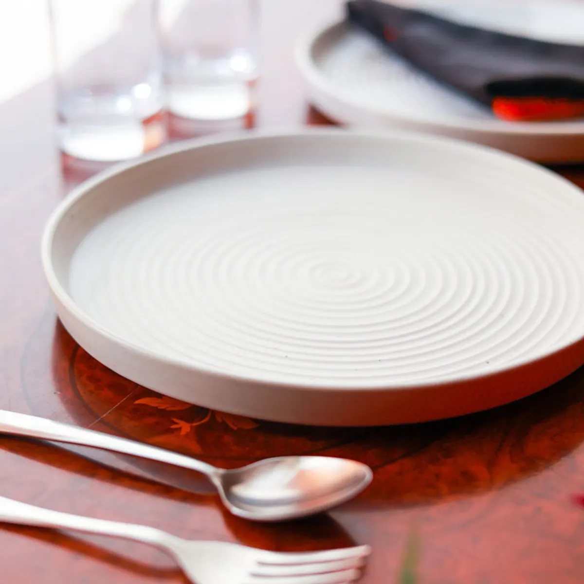 Close view of a white ceramic dinner plate with raised circular detailing