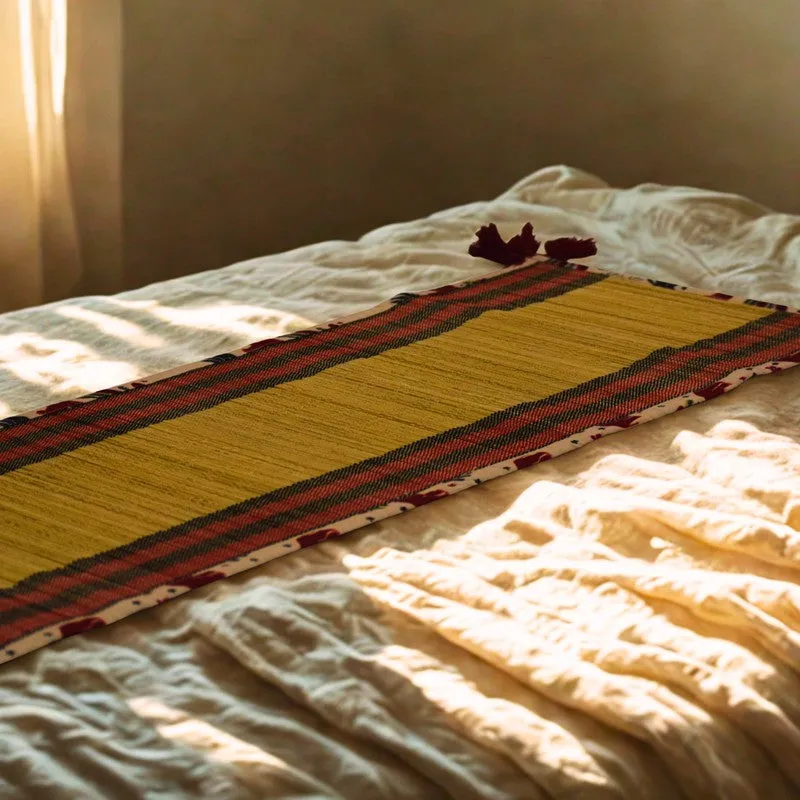 Beige and red bamboo table runner displayed across a softly lit bed