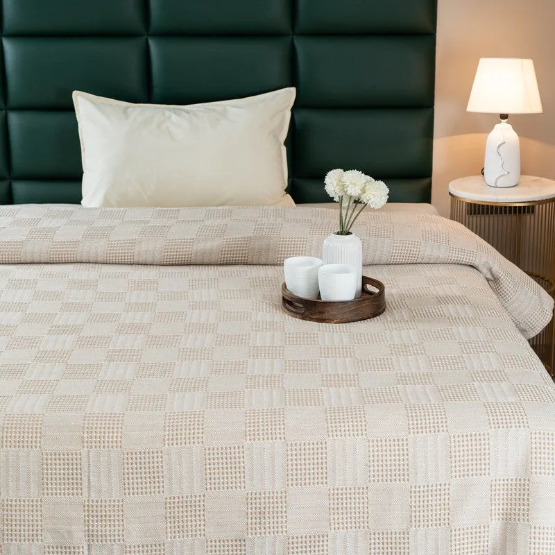 Close view of beige textured bedsheet with geometric pattern on bed