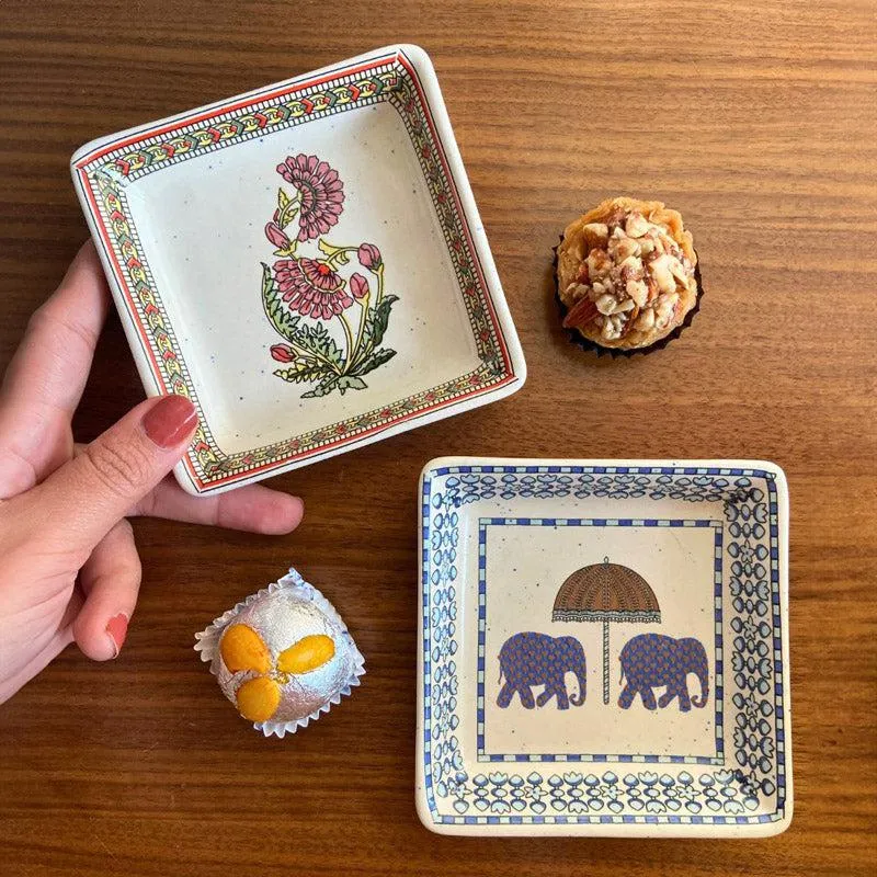 Two decorative square platters showing floral and elephant motifs with desserts