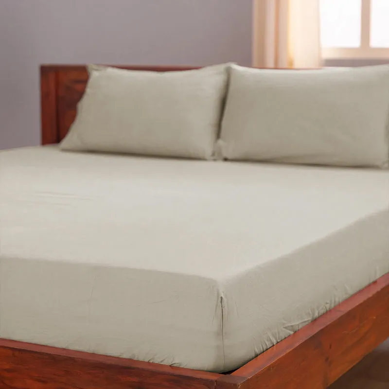 Beige fitted sheet stretched over a wooden bed with matching pillows