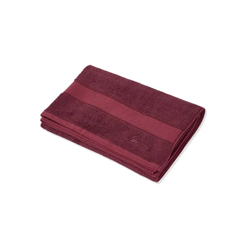 Folded maroon bath towel on a plain white background