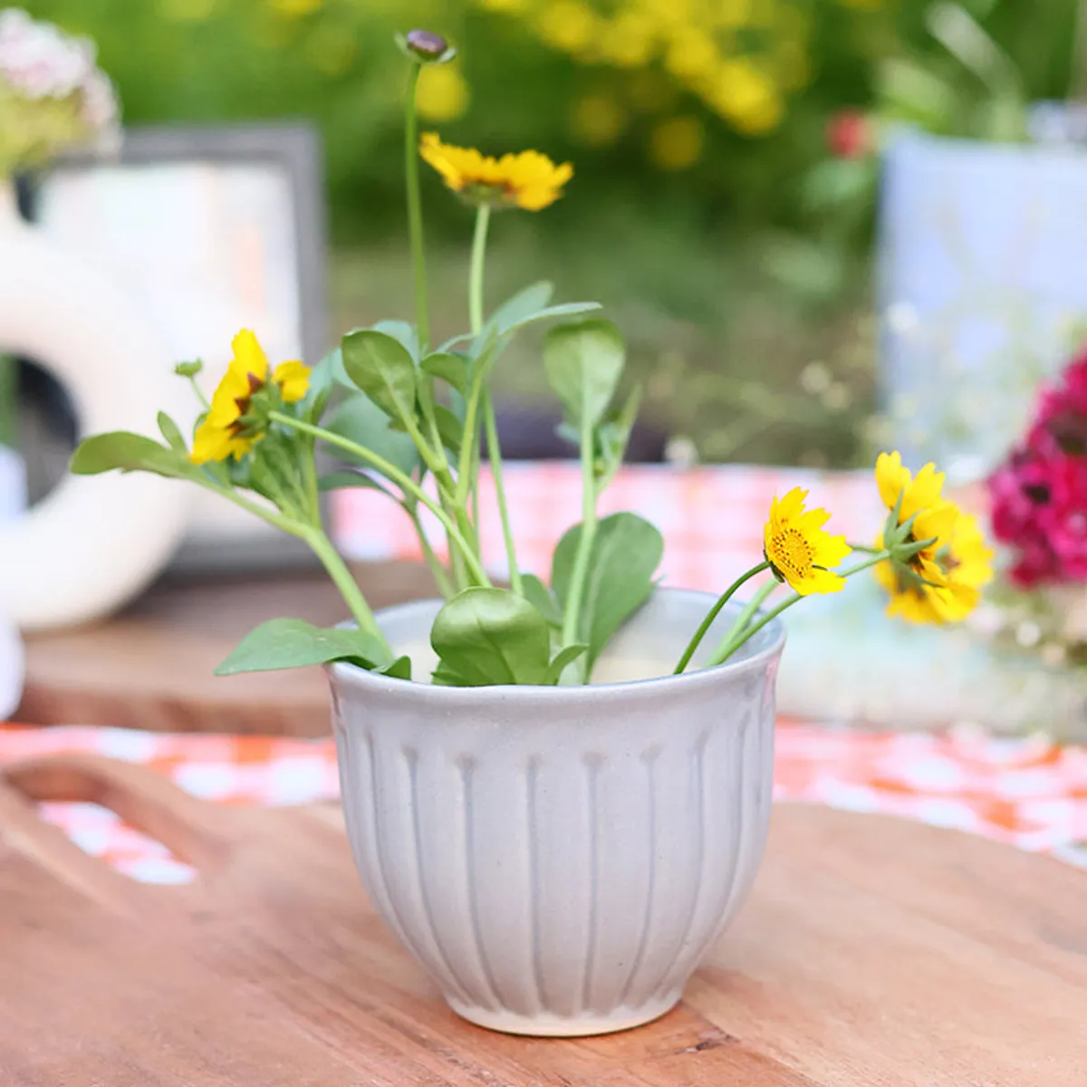 Grey ribbed planter with flowering plants on an outdoor table