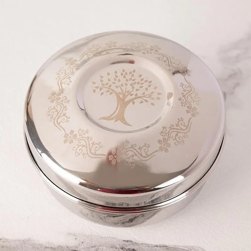 Close-up of a silver lid featuring a tree of life motif and decorative border
