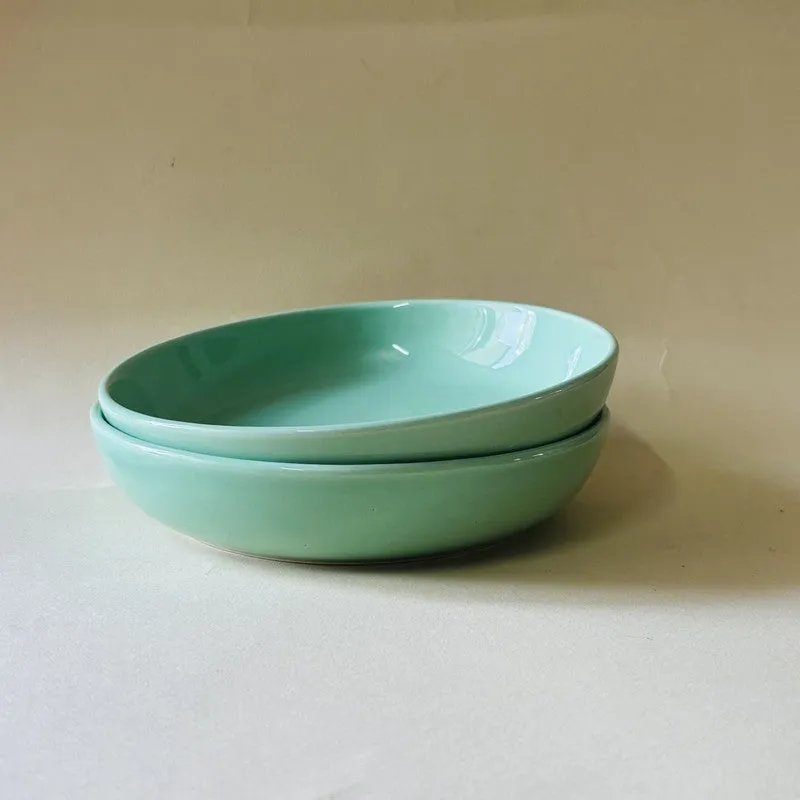 Two glossy green ceramic bowls stacked together