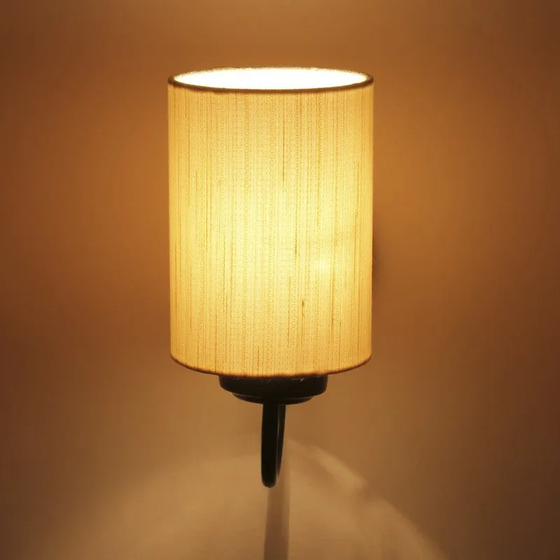 Close view of lit beige cylindrical wall lamp casting warm light