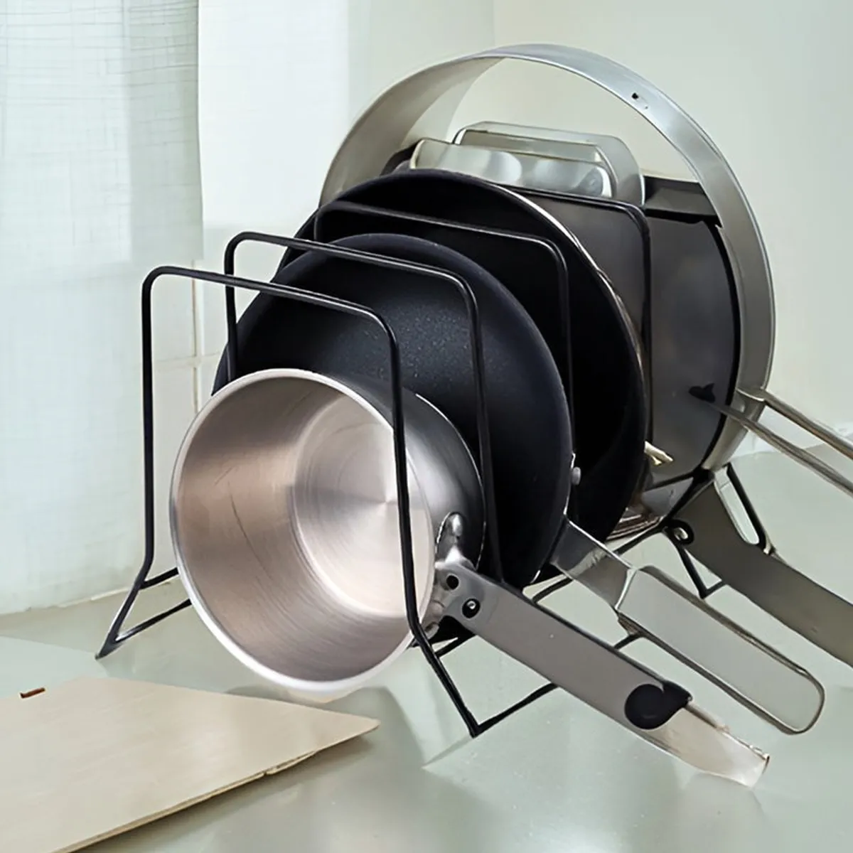 Black metal kitchen rack holding pans and lids upright