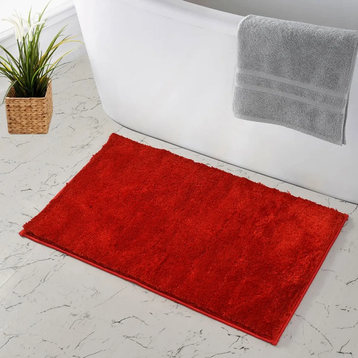 Red rectangular bath mat beside a bathtub