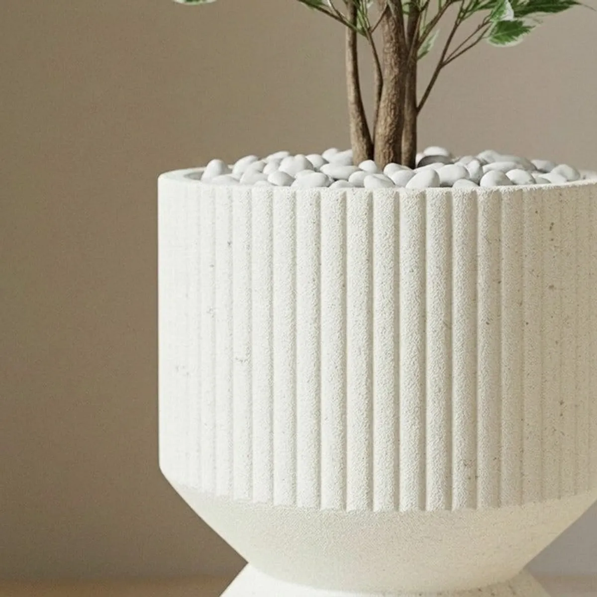 Close-up of a leafy plant in the ribbed off-white planter.